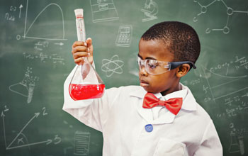 a boy in a lab coat with a red bowtie in front of a blackboard holding a flask with a red liquid inside.